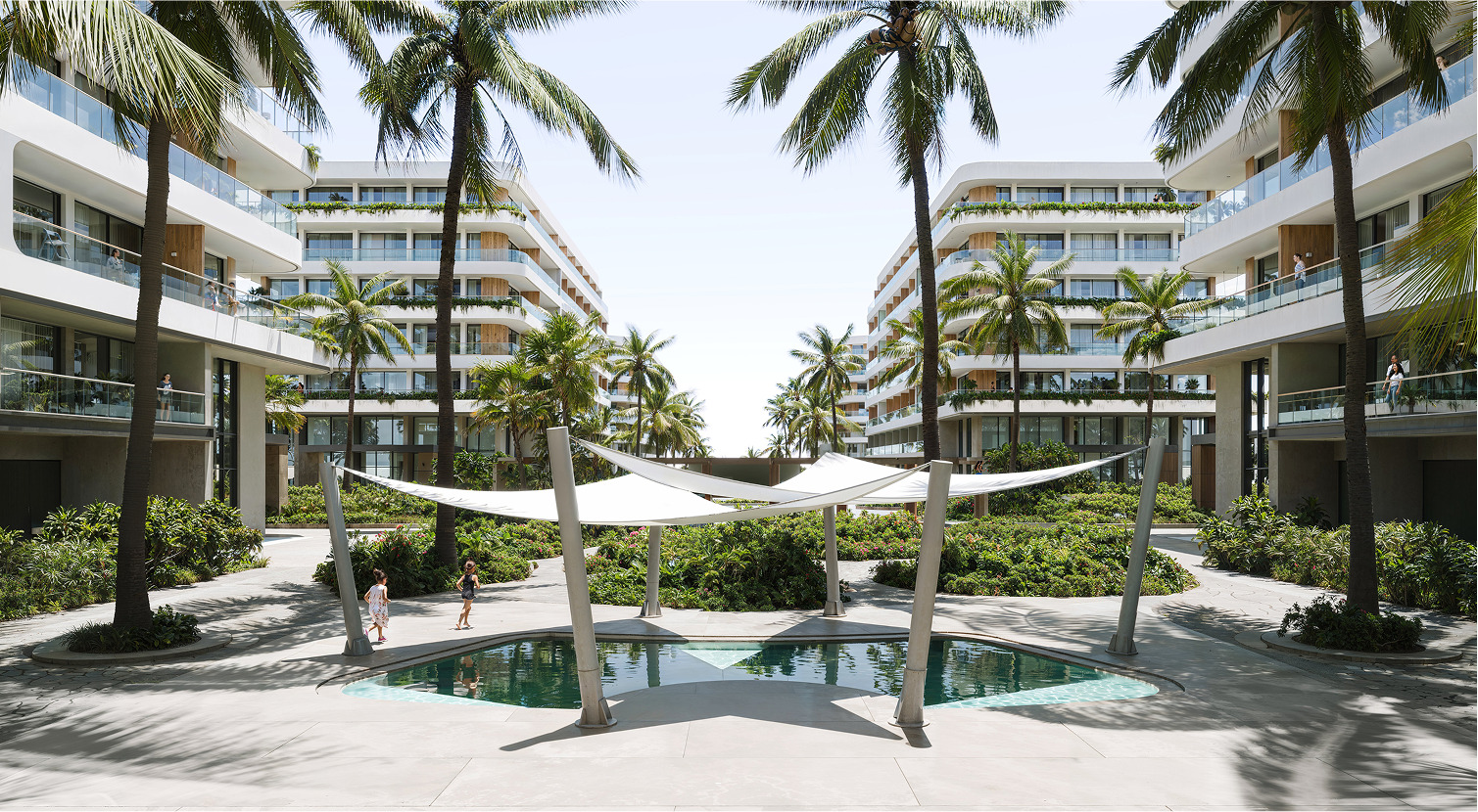 Luxury Palm Beach resort courtyard with pool and shade structure.