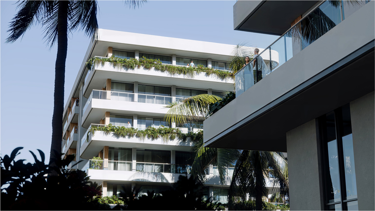 Modern Palm Beach building with balconies and lush tropical landscaping.