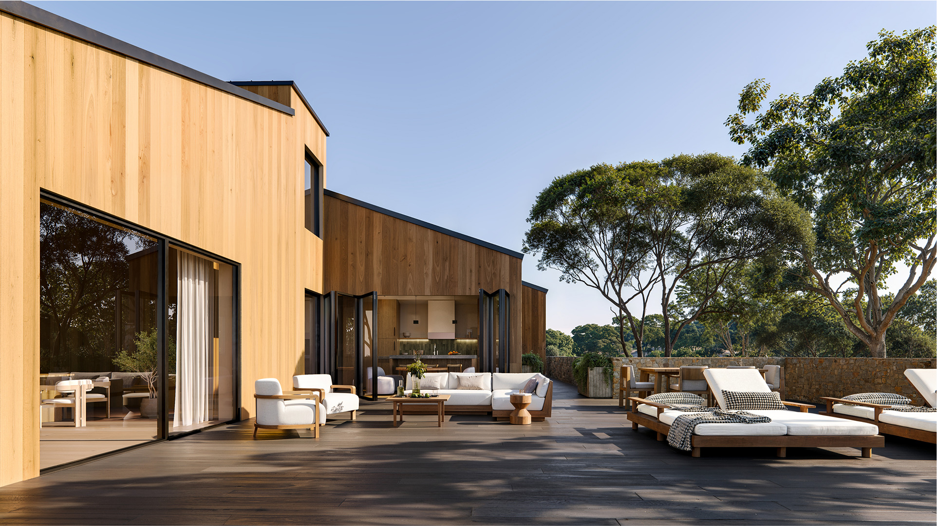 Modern wooden home's outdoor deck with lounge furniture and views of trees. Chalk Hill case study.