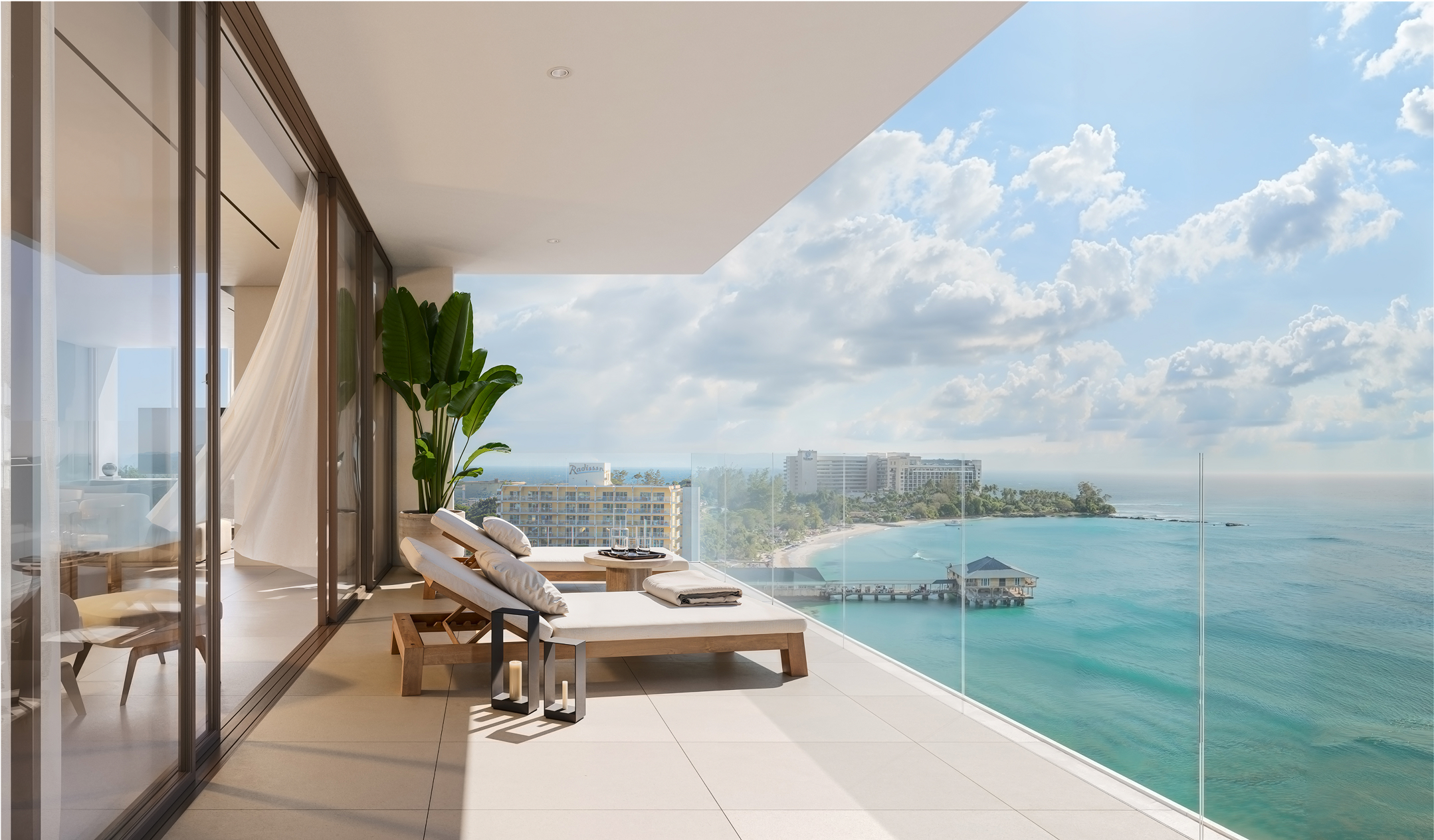 Luxury balcony at One Carlisle Bay with ocean views and lounge chairs.