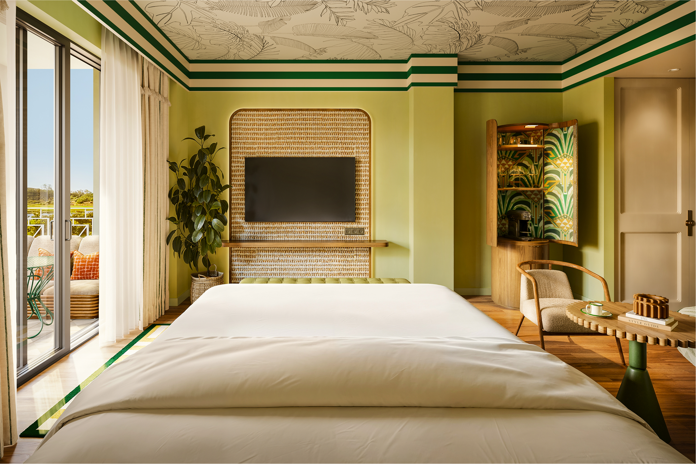 Luxurious Kimpton hotel room with a king-size bed, tropical decor, and balcony view.